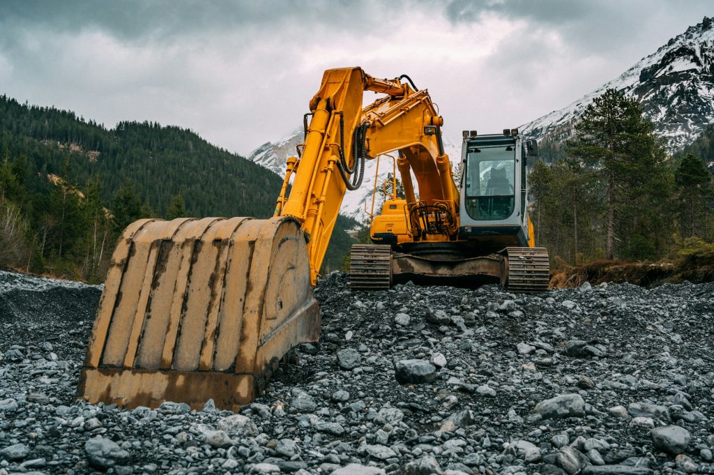 Yellow and black excavator working on rocks